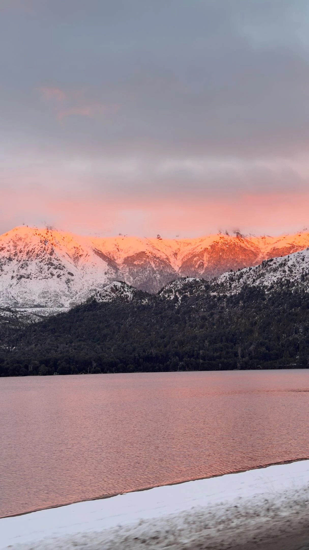 Montanhas nevadas refletidas em um lago ao pôr do sol