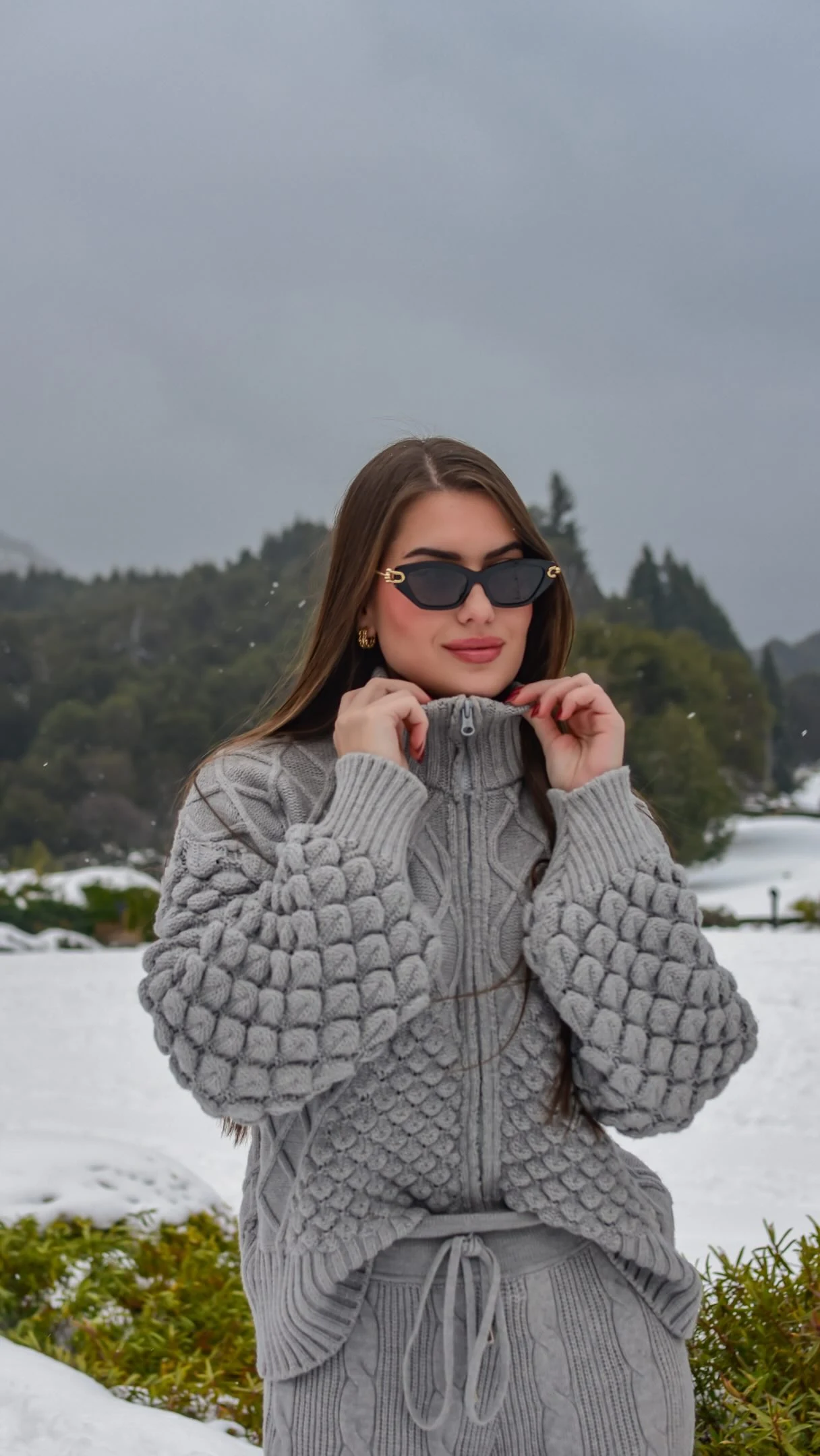 Raissa Dámian de óculos escuros e suéter cinza em viagem de inverno