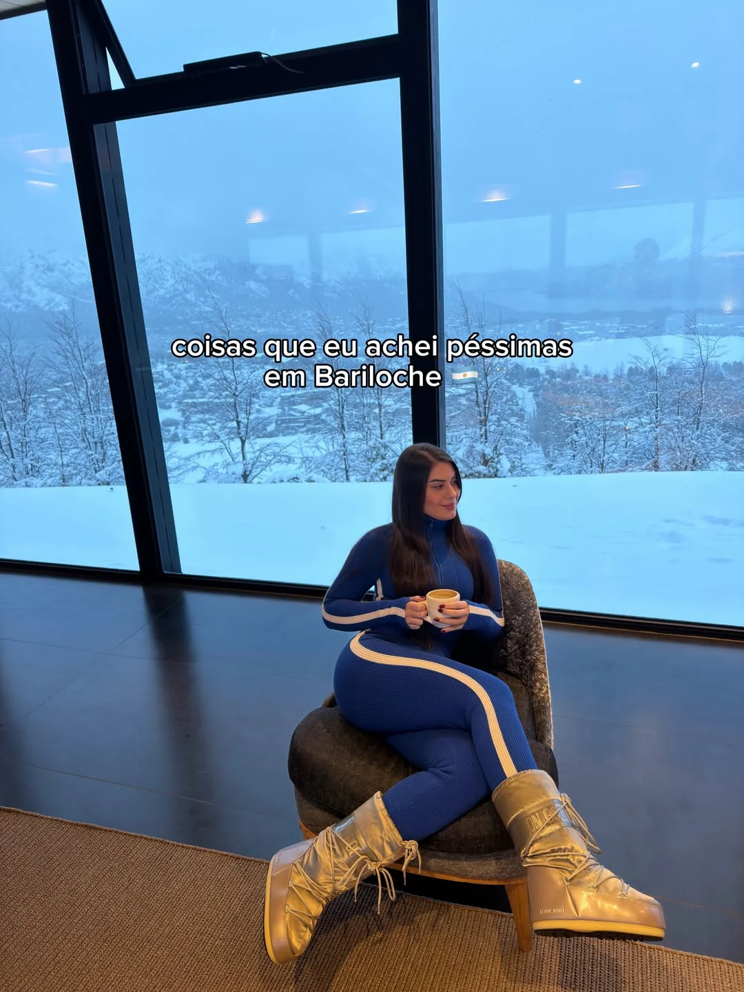 Raissa Dámian sentada diante de uma janela com paisagem de neve
